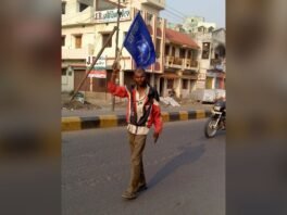 सड़क पर बसपा का झंडा लिए एक कार्यकर्ता