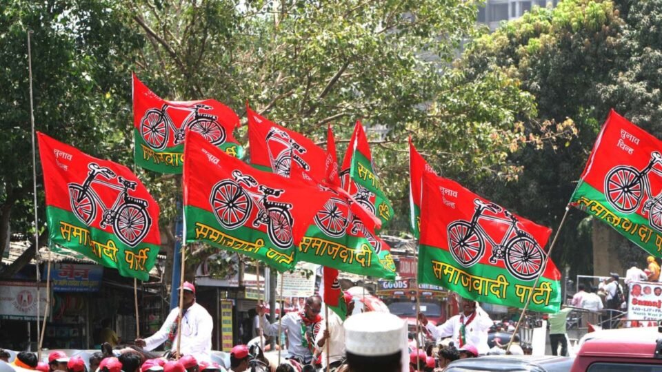 समाजवादी पार्टी के लाल-हरे झंडों के साथ सड़क पर मार्च करते पार्टी कार्यकर्ता
