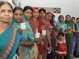 वाराणसी के एक मतदान केंद्र पर पहचान पत्र लेकर कतार में खड़ी महिला मतदाता